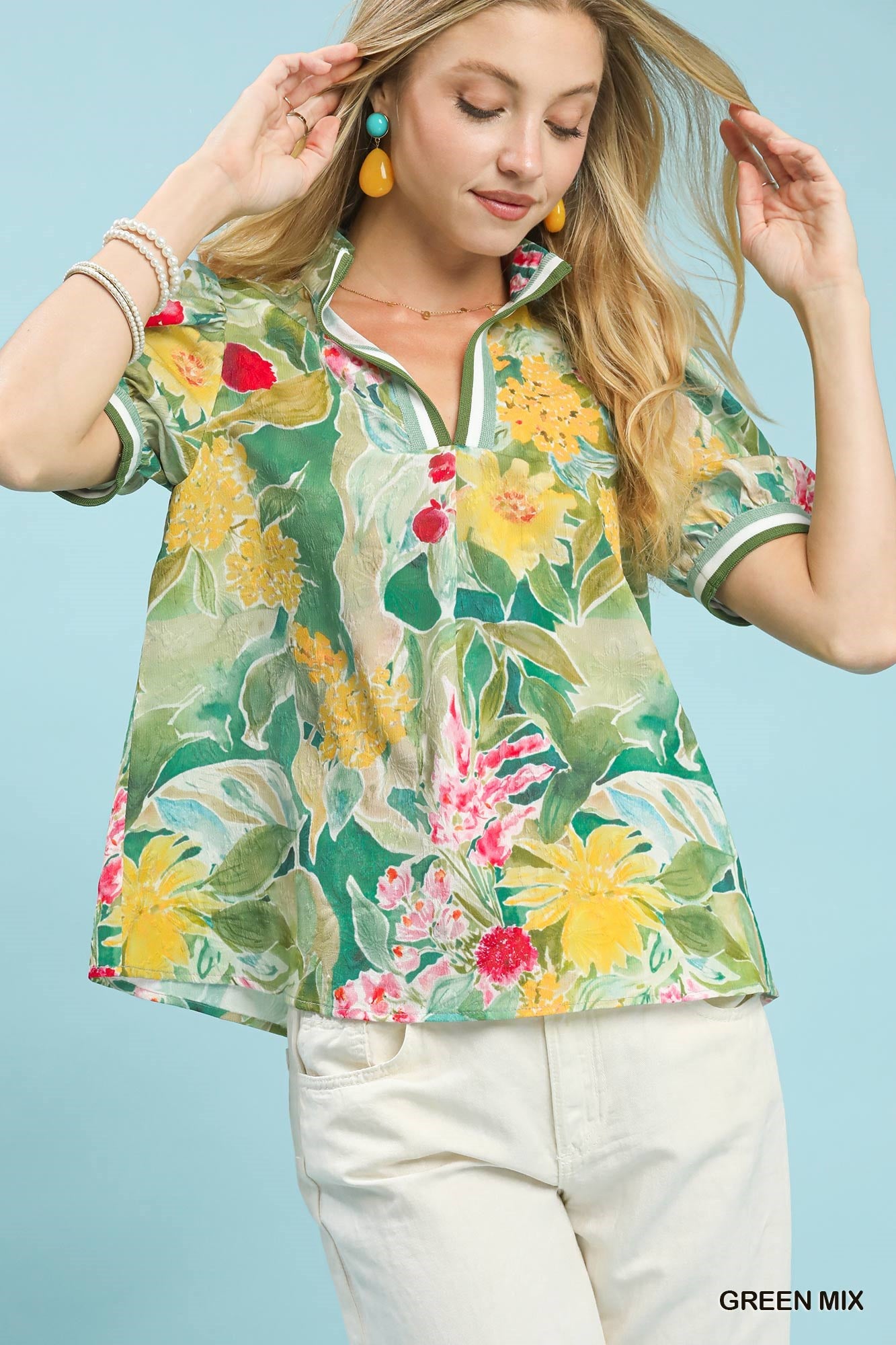 Woman wearing a colorful floral blouse against a light blue background