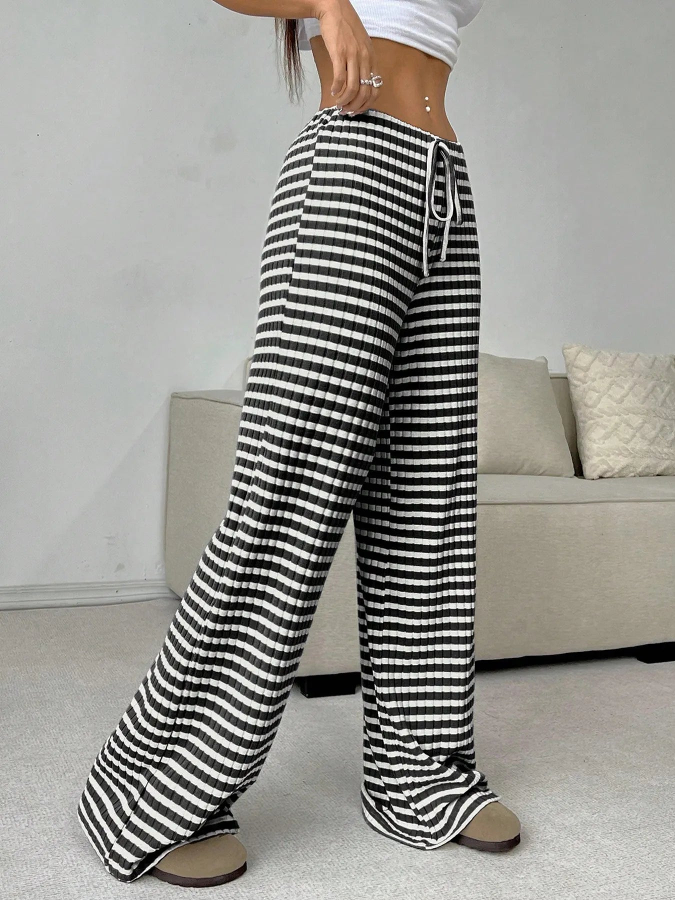 Person wearing black and white striped pants in a room with a sofa.