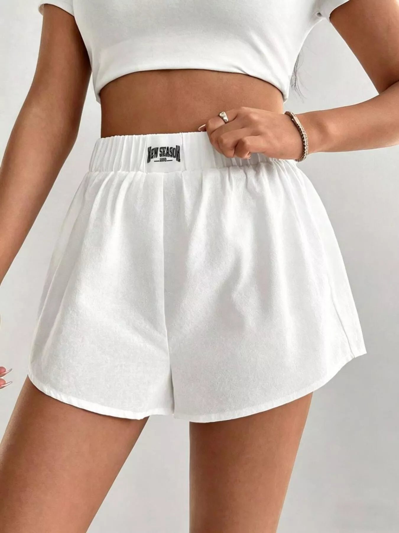 White athletic shorts with a brand logo worn by a person on a light gray background