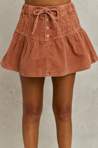 Brown corduroy skirt with buttons on a neutral background