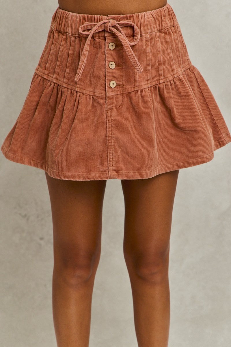 Brown corduroy skirt with buttons on a neutral background