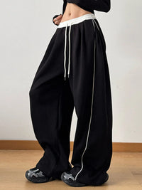 Black wide-leg pants with white drawstring and trim on a plain background