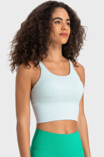 Woman wearing a light blue sports bra and green shorts on a white background