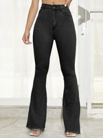 Person wearing black flared jeans in a minimal indoor setting