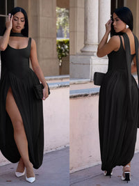 Woman wearing a black dress with a slit, standing outdoors.
