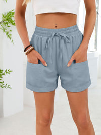 Person wearing light blue shorts with a white background