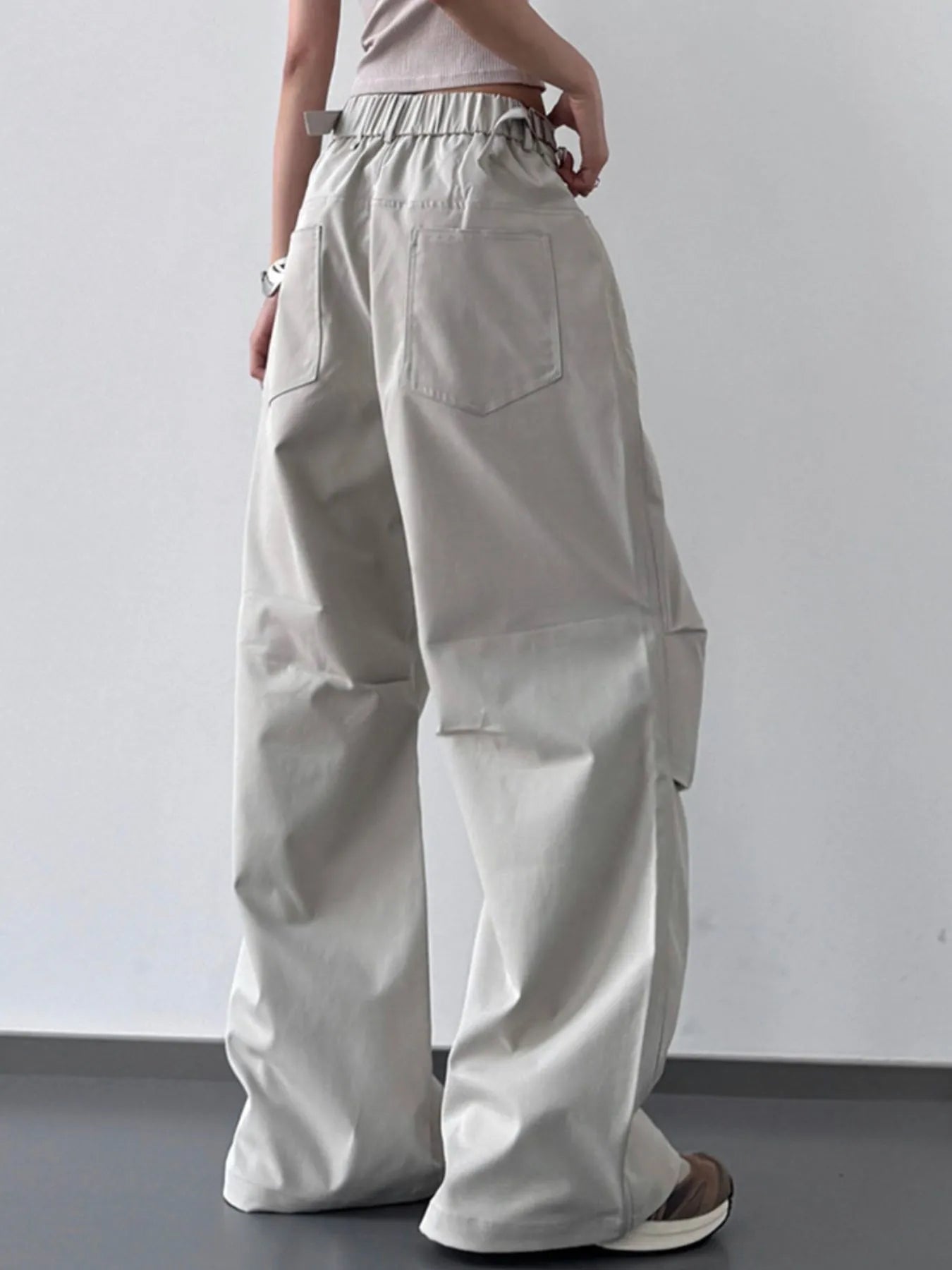 Person wearing beige wide-leg pants against a plain background