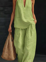 Person wearing a green outfit holding a woven bag against a dark background