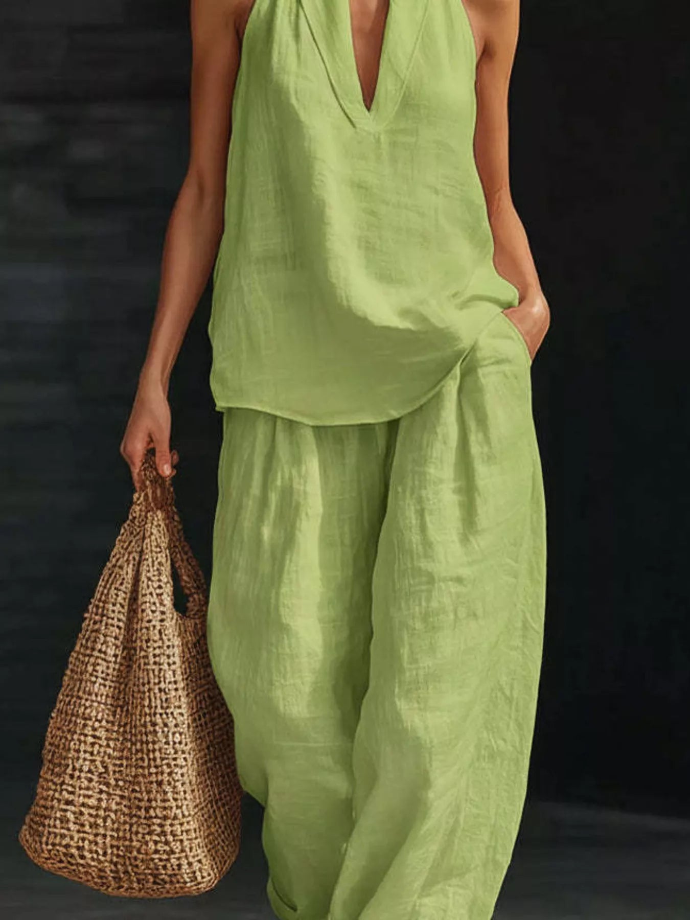 Person wearing a green outfit holding a woven bag against a dark background