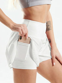 Person wearing white athletic shorts with a pocket holding a phone on a light background
