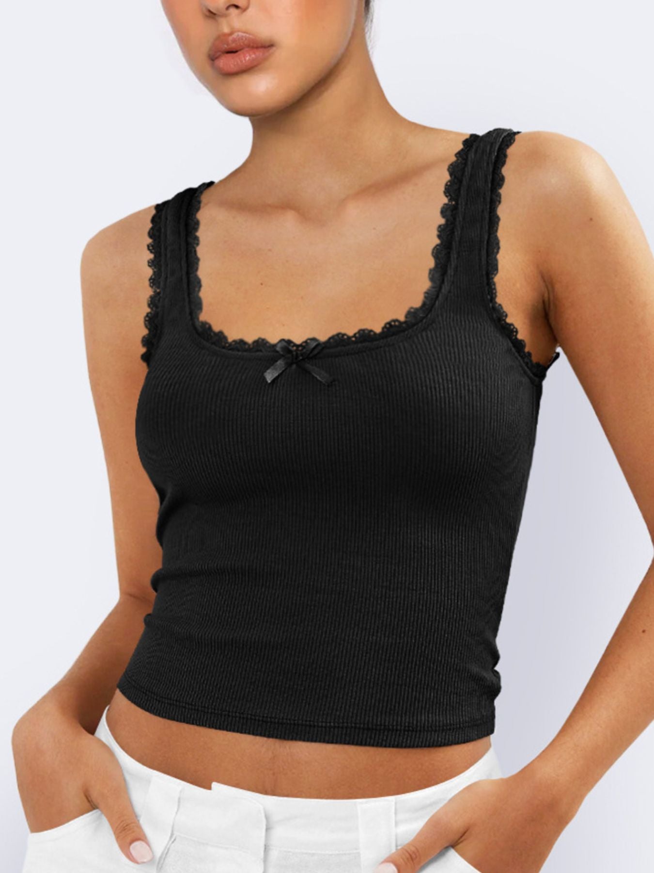 Black ribbed tank top with lace details worn by a model on a light gray background