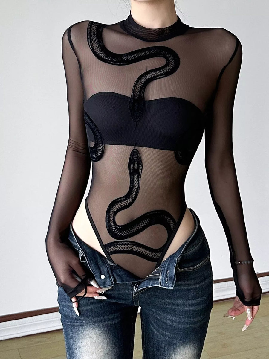 Person wearing a black sheer outfit with snake design and blue jeans.