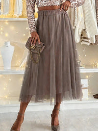 Person wearing a long beige skirt with a matching handbag in a store setting