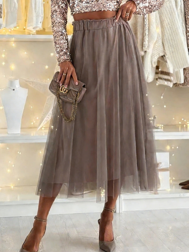 Person wearing a long beige skirt with a matching handbag in a store setting