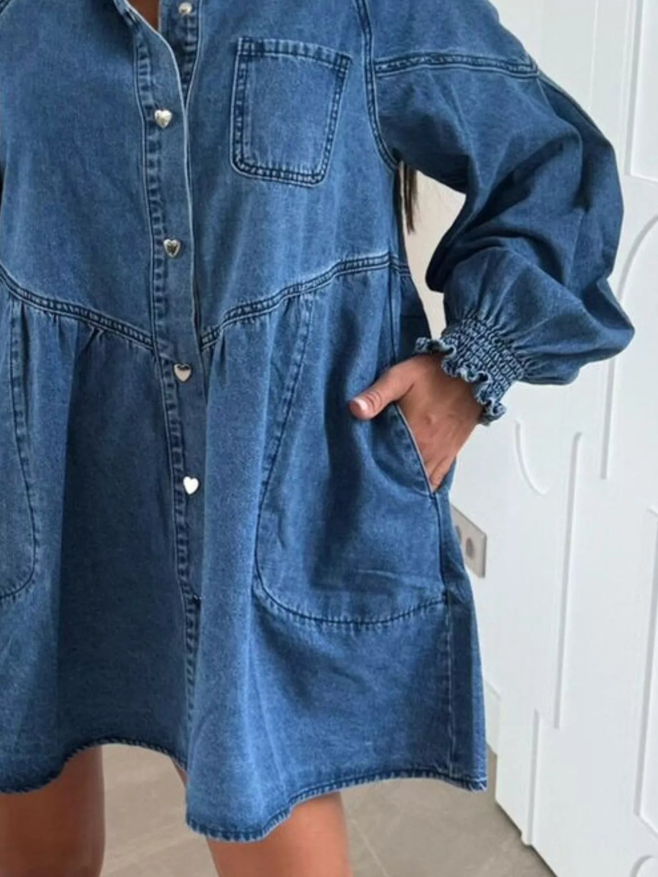 Blue denim dress worn by a person with a white wall background