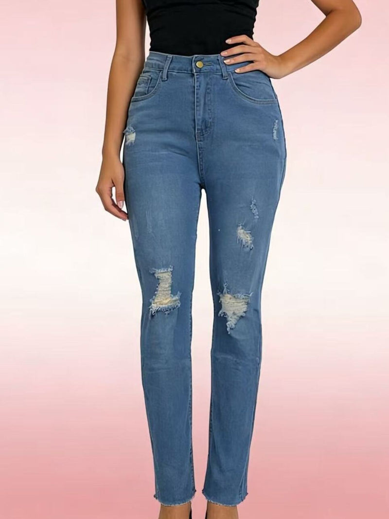 Person wearing distressed blue jeans on a pink background