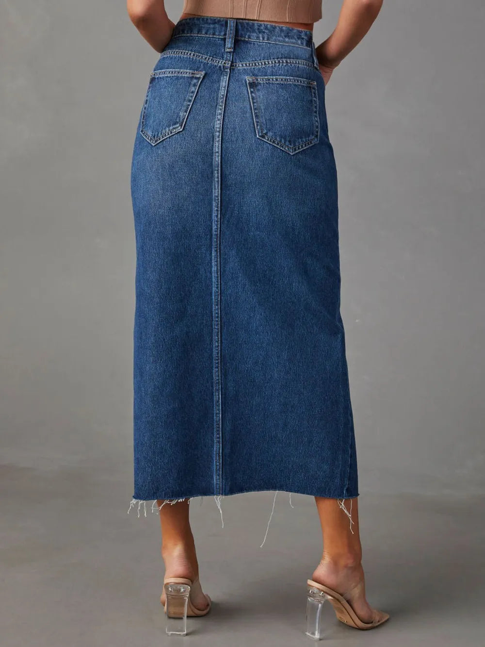 Person wearing a blue denim skirt on a gray background