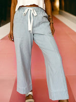 Person wearing light blue and white striped pants on a pink and white background
