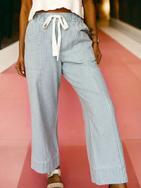 Person wearing light blue and white striped pants on a pink and white background