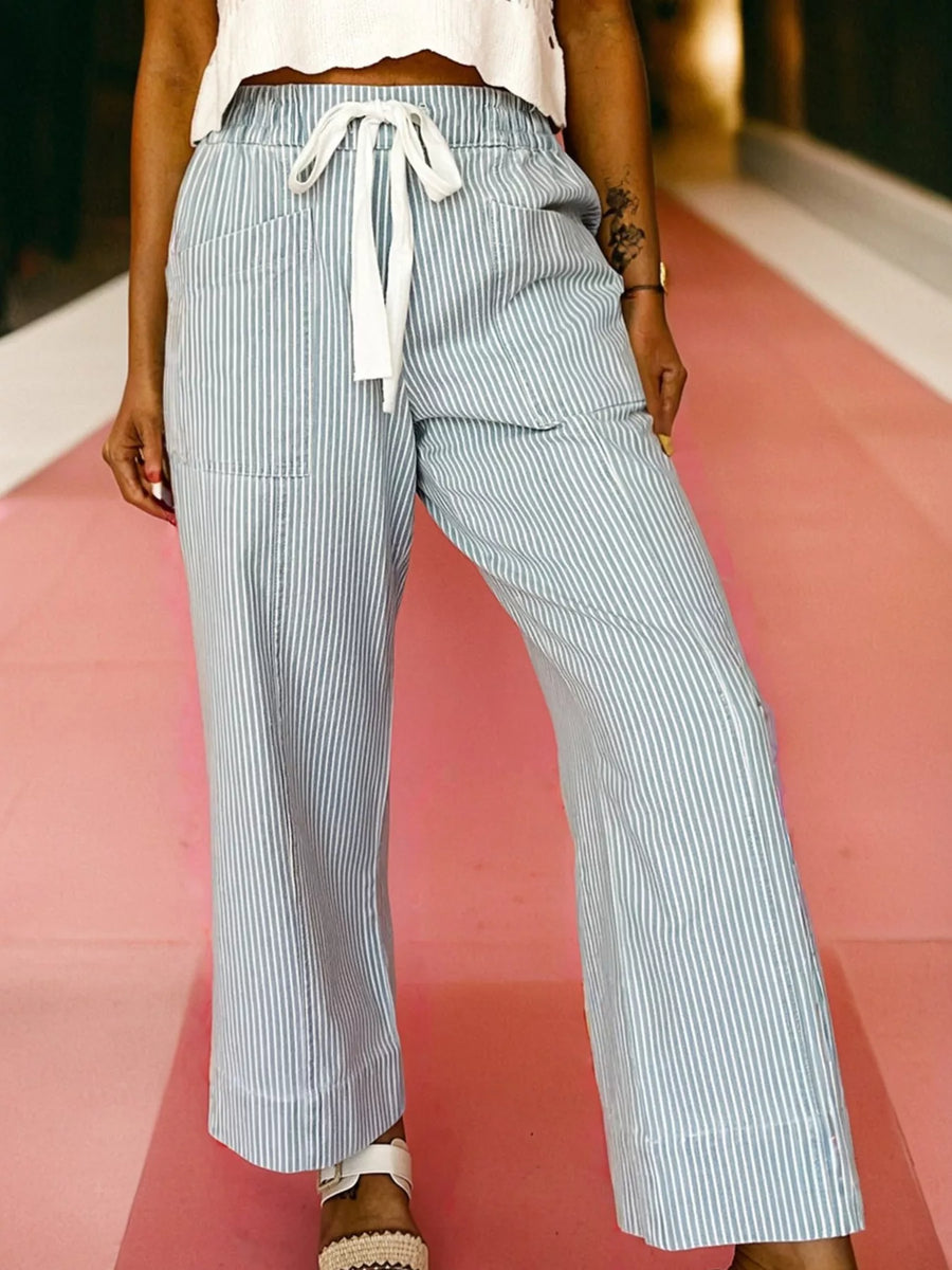 Person wearing light blue and white striped pants on a pink and white background