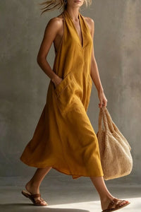 Woman in a mustard yellow dress holding a beige bag against a neutral background
