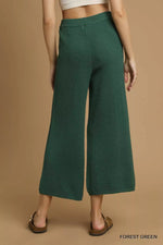 Green textured pants worn by a person on a brown background