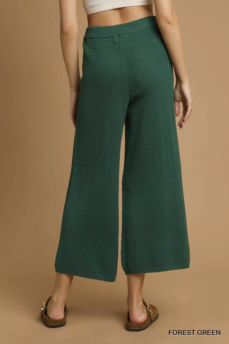 Green textured pants worn by a person on a brown background