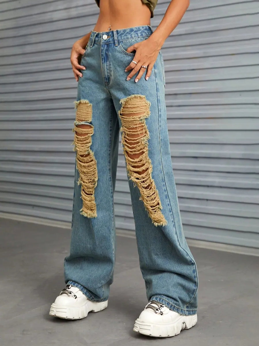 Person wearing distressed blue jeans with a gray background