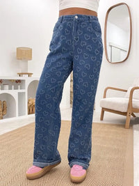 Person wearing blue jeans with heart pattern in a room.