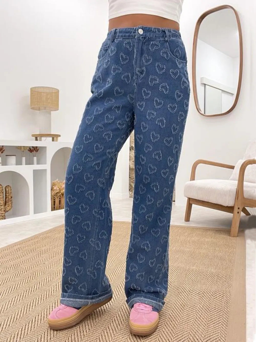 Person wearing blue jeans with heart pattern in a room.