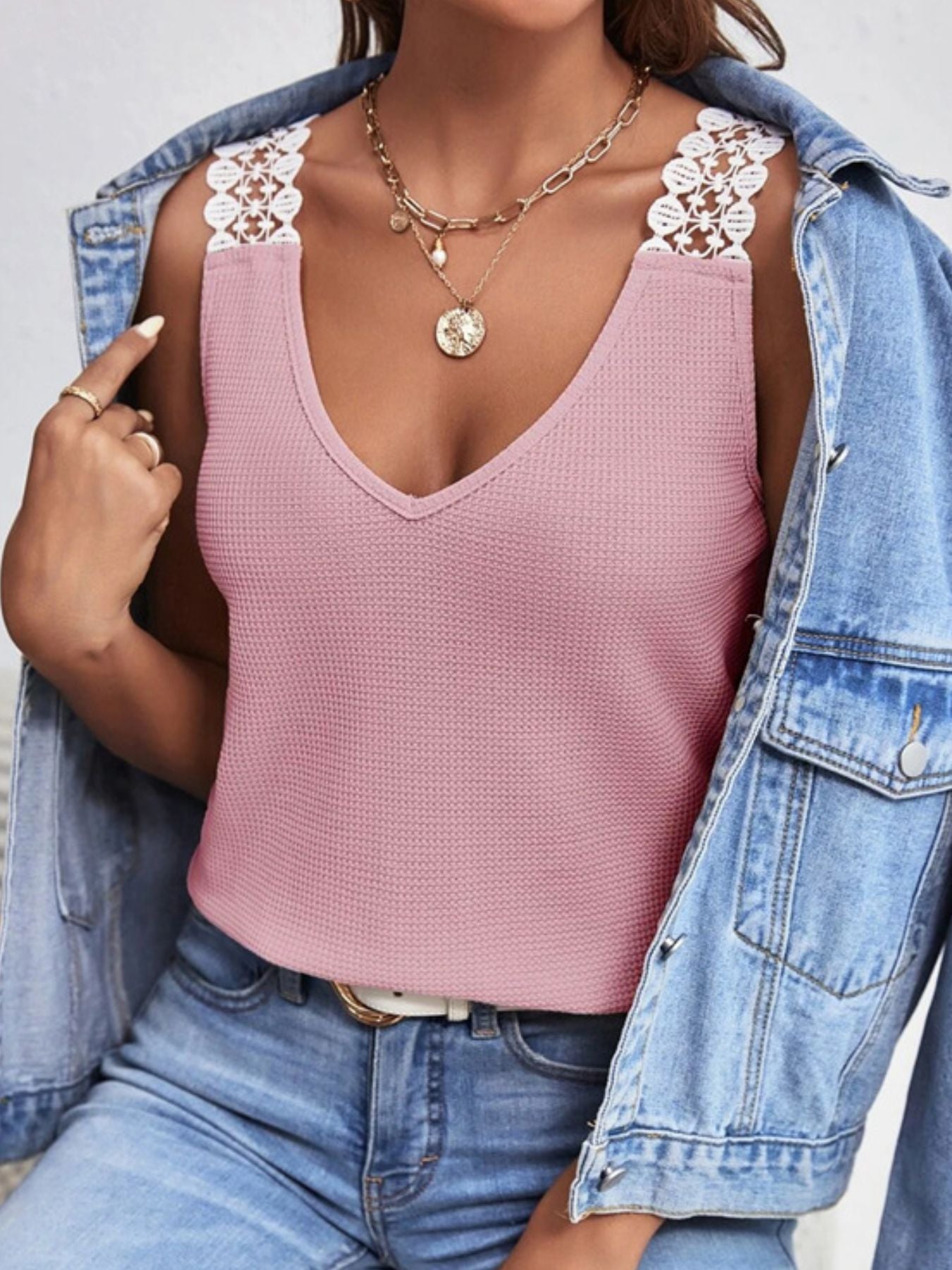 Person wearing a pink top with lace details and a denim jacket.