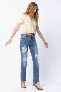 Woman wearing a yellow striped shirt and blue ripped jeans on a white background