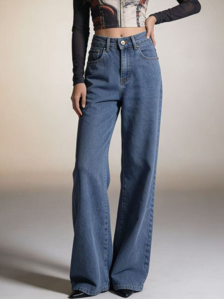 Person wearing blue flared jeans on a plain background