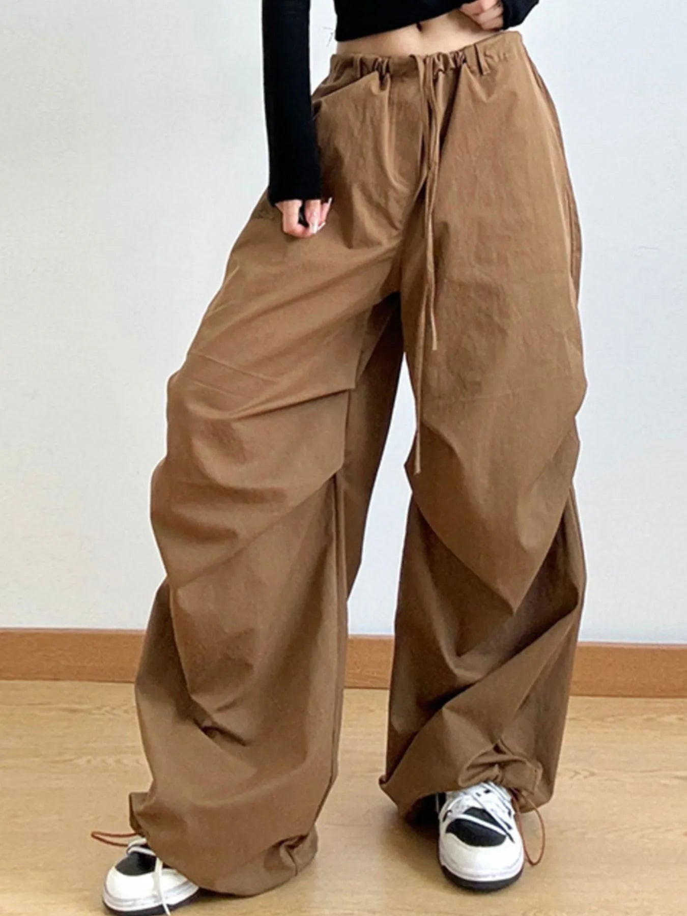 Person wearing brown wide-leg pants on a plain background