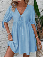 Woman wearing a light blue dress with a white brick wall background