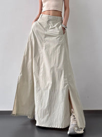 Person wearing a long beige skirt with a plain background