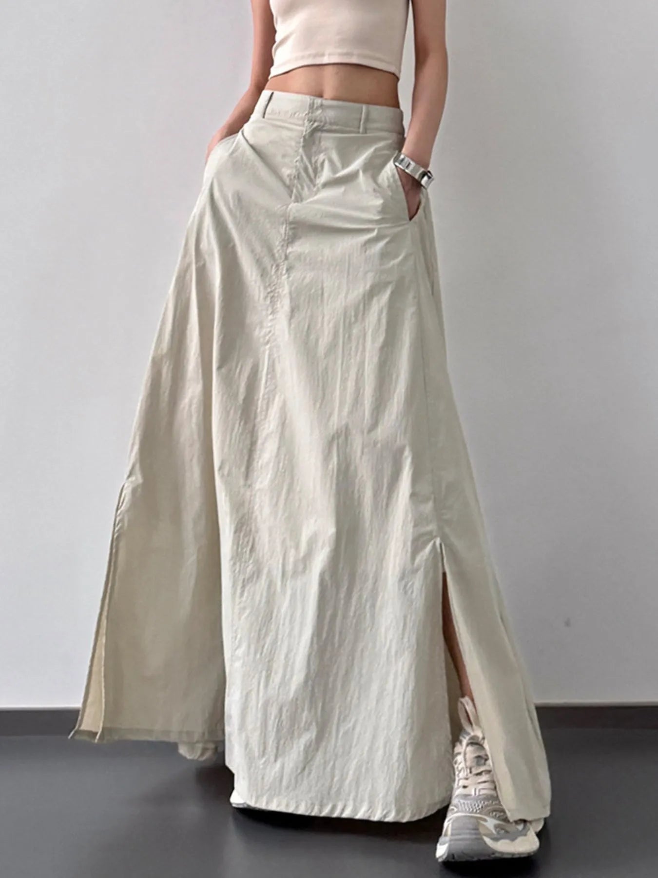 Person wearing a long beige skirt with a plain background