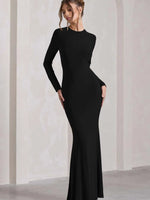 Woman wearing a black long-sleeve gown against a plain background