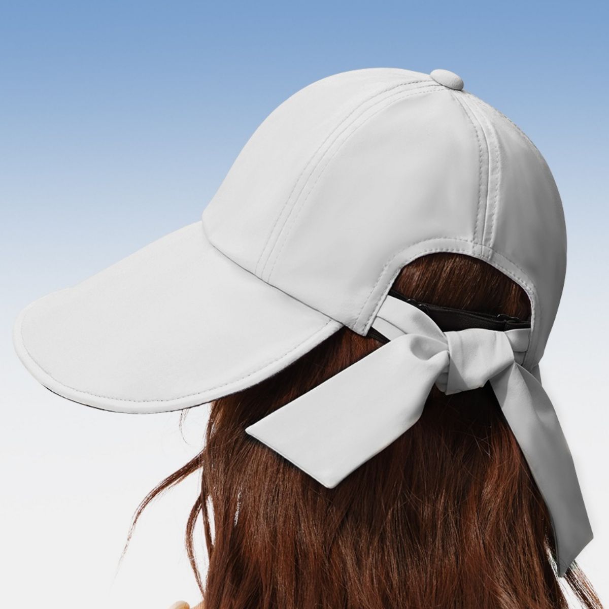 White baseball cap with a large bow on a clear blue sky background