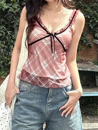 Person wearing a pink plaid top with a bow and blue jeans outdoors.