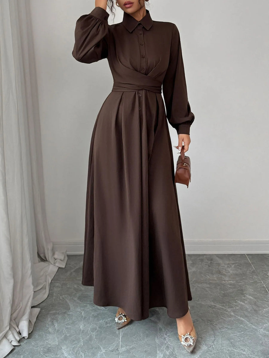 Woman wearing a brown dress standing in a room with light gray walls and a gray floor.