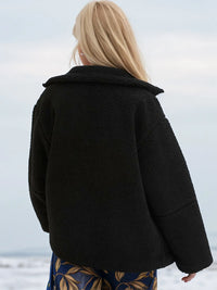 Person wearing a black coat with a blurred background