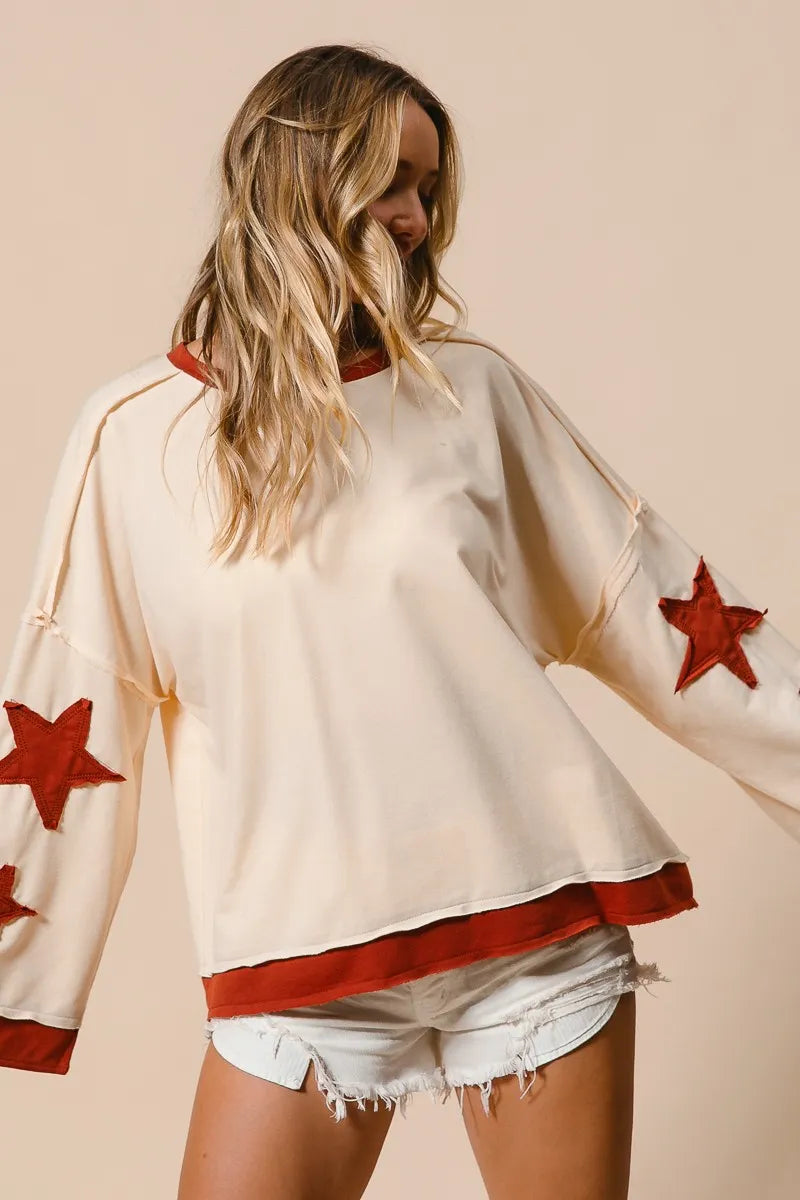 Woman wearing a white top with red star designs on a beige background
