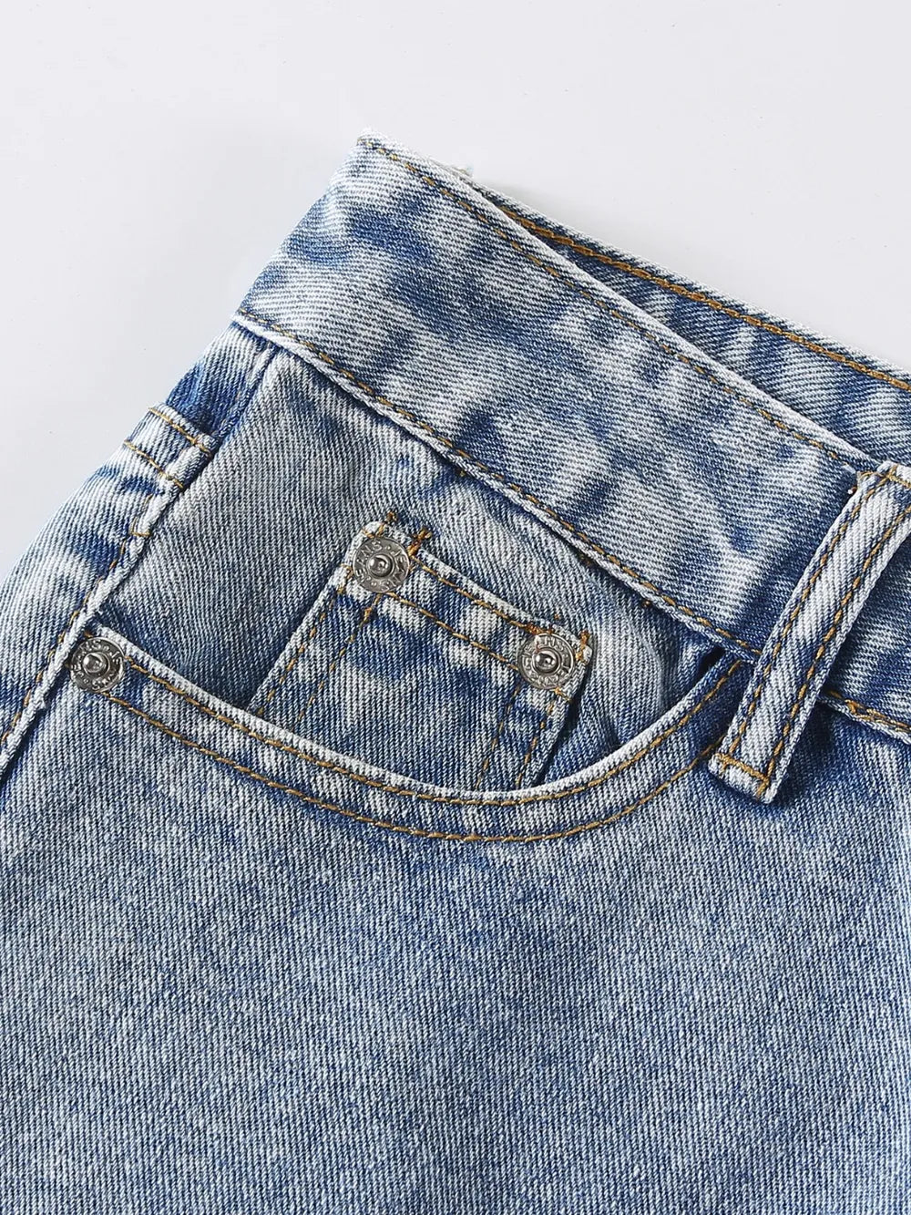 Close-up of a blue denim pocket with stitching details on a light gray background