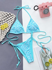 Blue leopard print bikini set on a gray and white background with a pink phone and lemon slices.