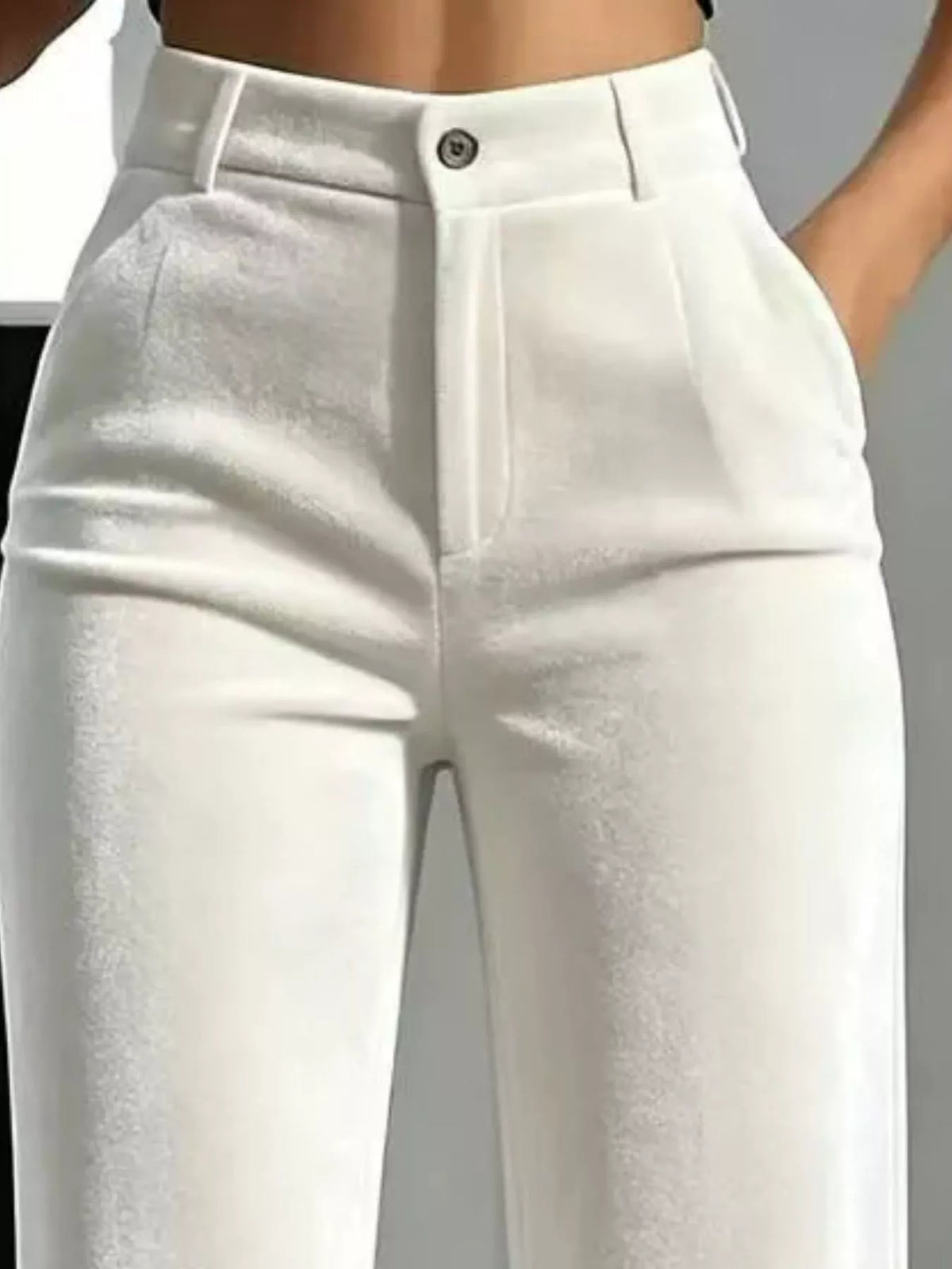 White high-waisted cropped pants with a structured waistband, front pleats, and a single button closure, shown on a model cropped from the waist down.
