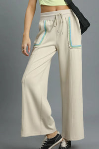 Beige wide-leg pants with blue accents on a gray background
