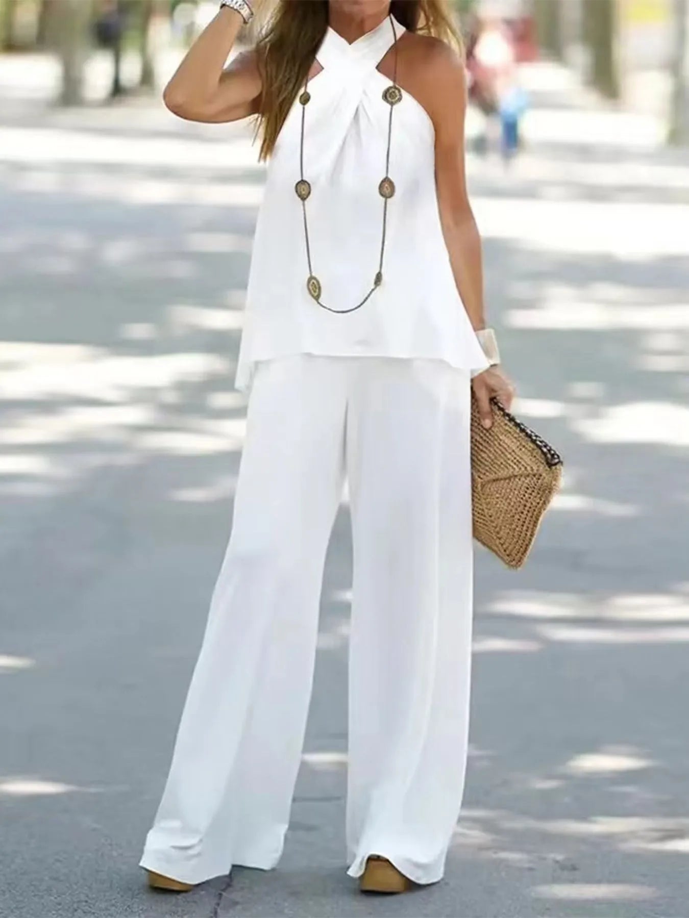Woman wearing a white outfit with wide-leg pants on a street.
