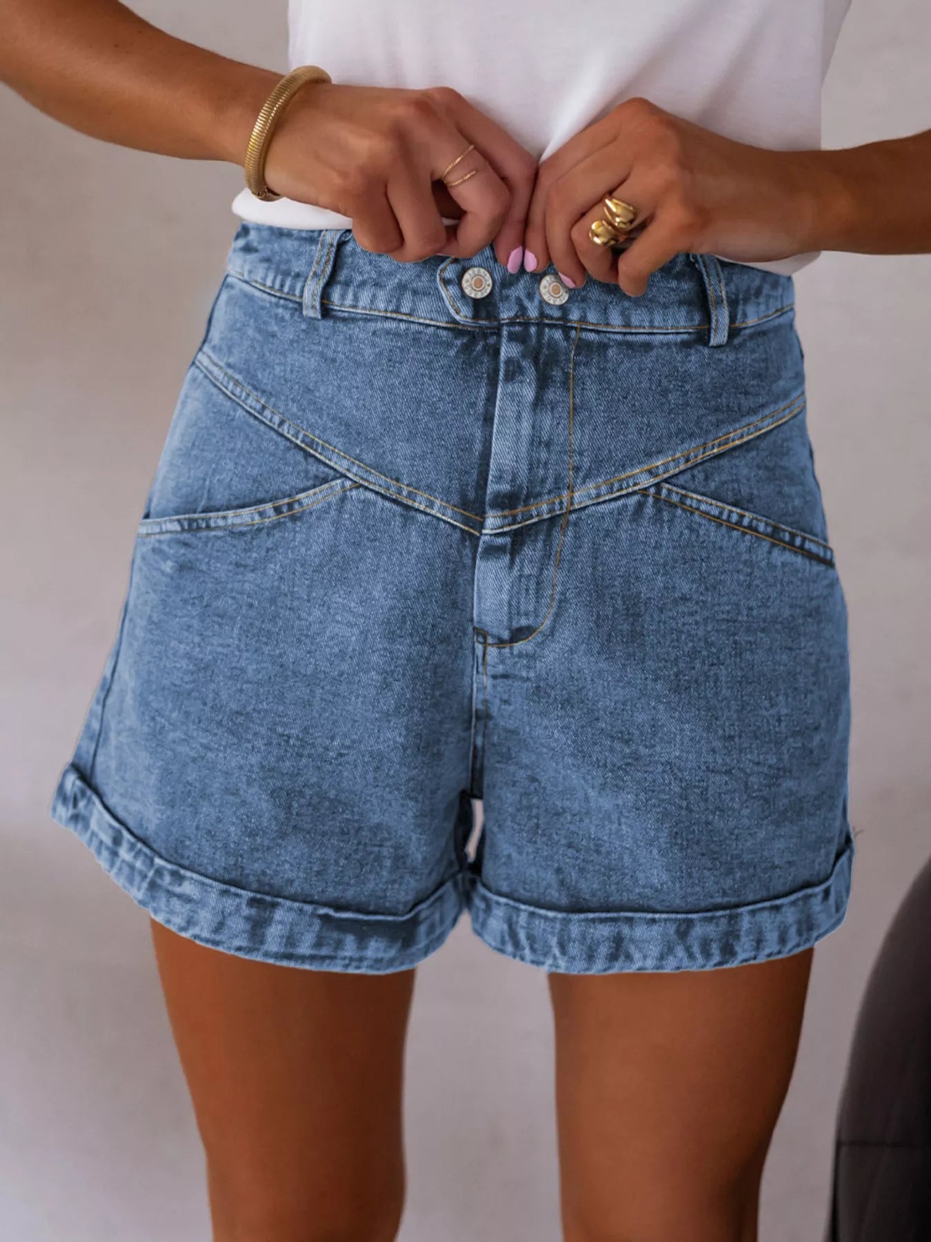 Person wearing blue denim shorts with a plain background