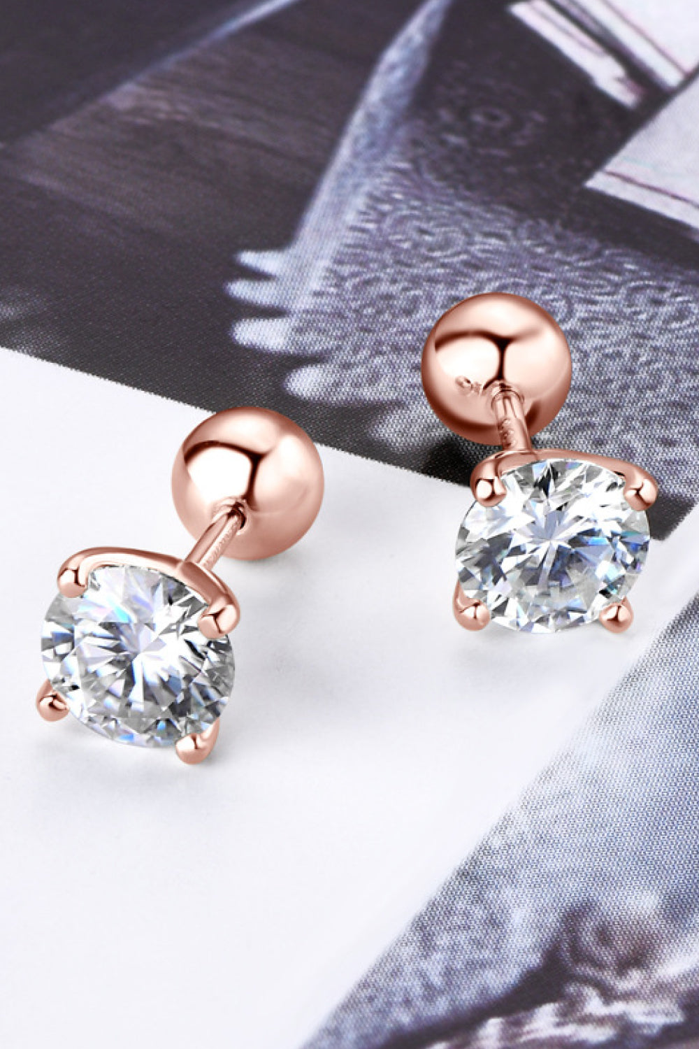 Rose gold stud earrings with clear gemstones on a light background